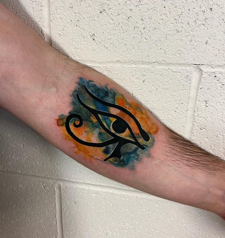 Yellow and blue watercolor eye of Horus Egyptian tattoo on a man's forearm.