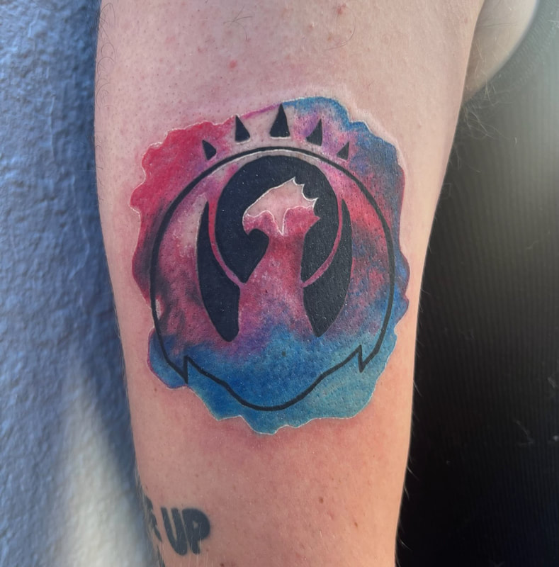 Izzet league Magic the Gathering tattoo in red and blue watercolor on a man's arm.