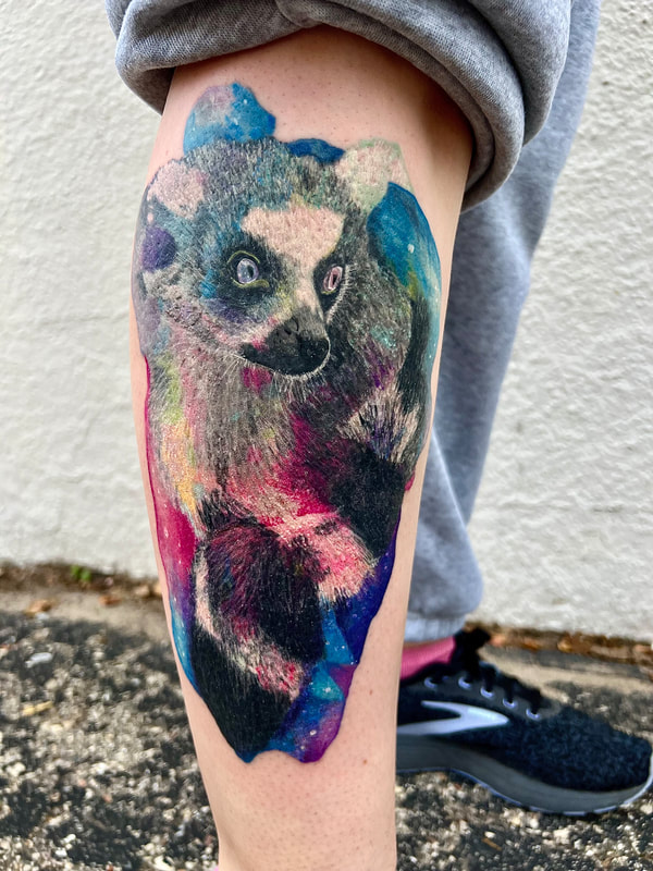 Rainbow color realism lemur tattoo with pink, purple, and blue galaxy on a woman's calf.