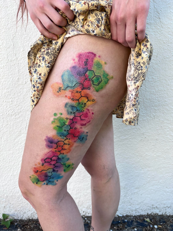 Rainbow watercolor endorphin molecular complex tattoo on an outer thigh.