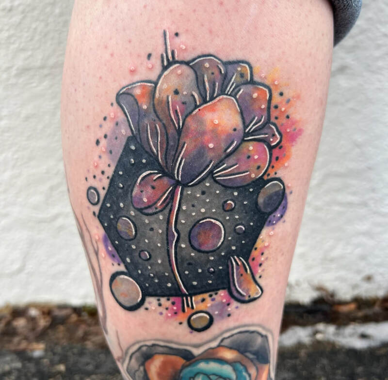 Pink, orange, and purple watercolor flower tattoo on a lower calf. 