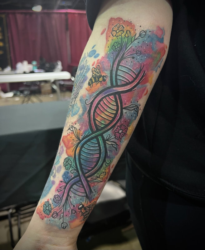 Rainbow watercolor DNA strand with flowers and bees on a forearm.