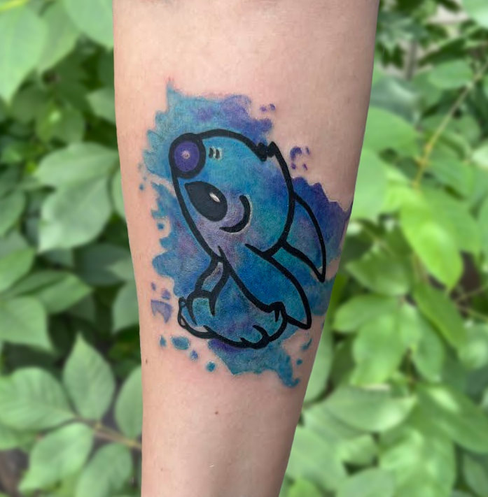 Blue watercolor Stitch tattoo on an arm.